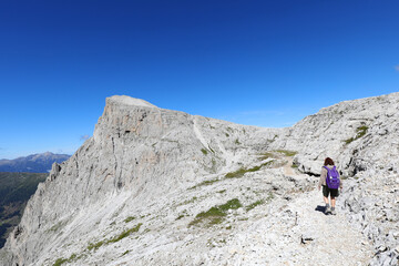 Fototapeta premium woman with backpack walks on the gravel path in the italian alps