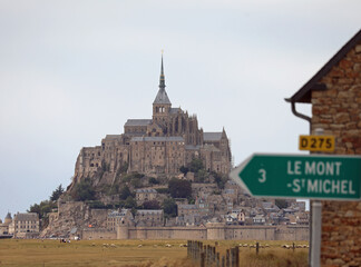 ancient abbey of Mont Saint Michel in Normandy in France and the road sign with the arrow