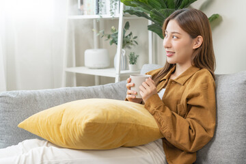 Obraz na płótnie Canvas Modern air humidifier during relaxed, rest on sofa, happy asian young woman, girl enjoying, drinking with aromatherapy steam scent from essential oil diffuser comfortable in living room at home.