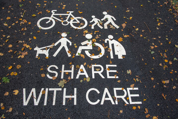 Fototapeta na wymiar Share with care sign on bicycle and walking path outdoors, covered with Autumn leaves 