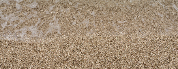 Fine gravel beach, close-up of fine pebble beach, washed over by clear sea water, on Croatian Adriatic coast. Copy space for your design. Web banner.