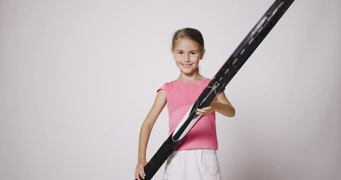 Young female tennis player with big oversize racket. Girl posing in pink sports outfit and smiling.