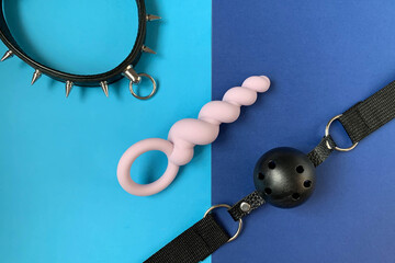 Gag, collar and butt plug on blue background. Sex shop assortment. Sex toys for BDSM