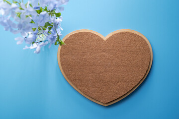 dirctly above blank heart shape cork board  and flower against blue background