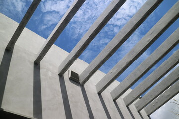 Obraz premium Underside of concrete walls and reinforced concrete beams structure of the building against the blue sky. Modern architecture. Minimalistic design, architecture detail