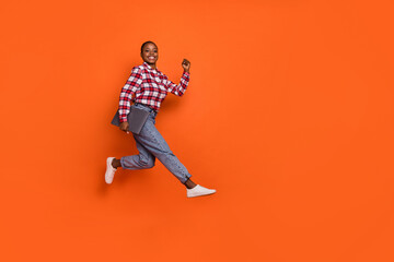 Full size portrait of active overjoyed lady rush fast hold wireless netbook isolated on orange color background