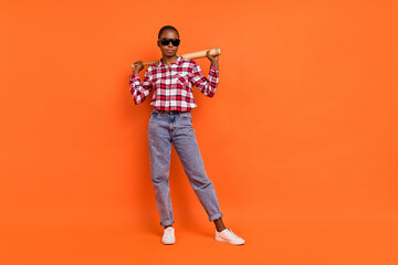 Full size portrait of focused calm person hold baseball bat wear sunglass isolated on orange color background