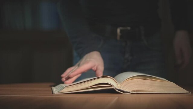 a man stands next to the table and flips through the pages of a book. slow motion video