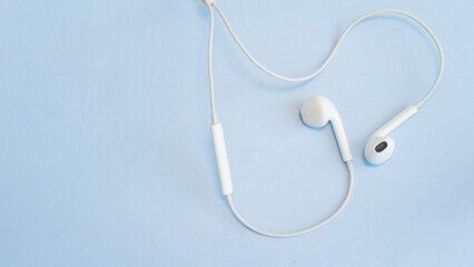 White wired headphones on a light blue background