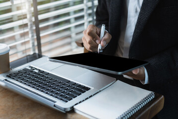 Business man holding tablet and typing laptop and notebook on the table.