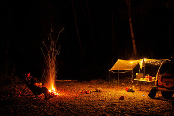 People are sitting at the campfire in autumn forest in the night