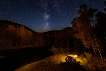 Tourist camping at the river bank at night under starry sky. Far East of Russia