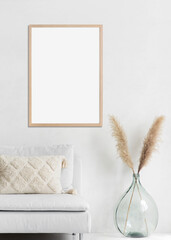 Blank frame mockup in modern interior design with trendy vase and sofa on empty white wall background, Vertical template for paintings, photo or poster. Artwork mock-up.