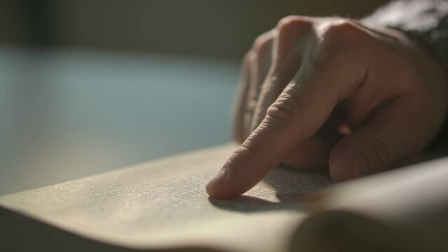 the man slowly runs his finger over the page of the book. slow motion video