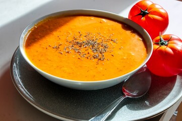 Close up photo of a bowl of tomato soup and basil