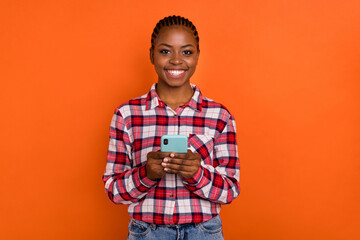 Portrait of cheerful pretty person hold use telephone write post comment isolated on orange color background