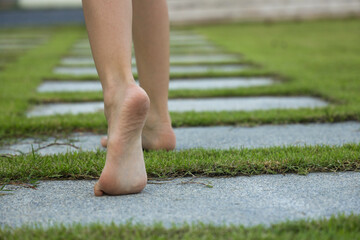 A barefoot little girl walks along the path in the garden.