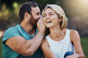Gossip, secret and funny story with couple on a romantic date in nature in Australia in summer. Man talking in a whisper into the ear of a young laughing woman while happy in a garden together - obrazy, fototapety, plakaty