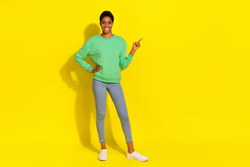 Full length body size view of attractive cheerful girl demonstrating copy space isolated over bright yellow color background