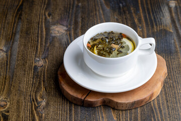 Green tea in a white cup during its brewing