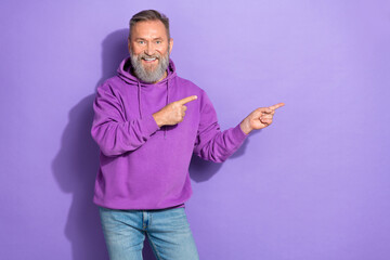 Portrait photo of senior attractive man wear hoodie fingers pointing empty space information isolated on pastel purple color background