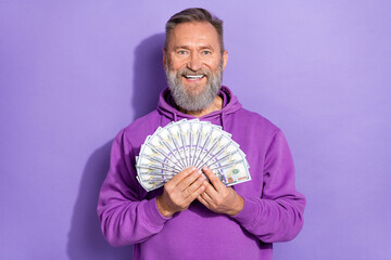 Portrait of handsome senior optimistic man with white gray beard hold a lot of dollar banknotes isolated on violet color background