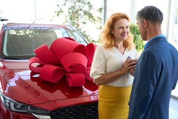Man and woman stand by the car with gift bow