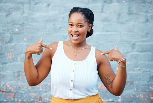 Black woman, pointing and happy feeling proud and self assured choosing herself against city building wall, mockup space or outside in Nigeria. Portrait of African model with a fun or playful gesture
