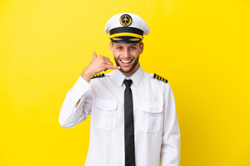 Airplane caucasian pilot isolated on yellow background making phone gesture. Call me back sign