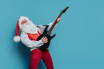 Emotional Santa Claus plays on electric guitar on blue background. Christmas music. New Year party 