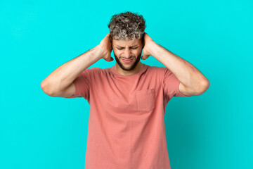 Young handsome caucasian man isolated on blue background frustrated and covering ears