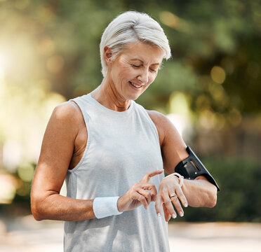 Senior woman, fitness and watch of running time in health and wellness for cardio exercise in nature. Active elderly female runner checking smartwatch to monitor training results in sports workout