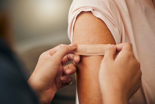 Covid, vaccine and plaster with a doctor and patient consulting in an appointment or checkup at home. Nurse, healthcare and trust with a health professional using a bandaid on an arm after medication
