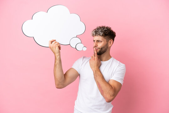 Young handsome caucasian man isolated on pink background holding a thinking speech bubble
