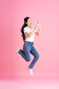 Full body image of Asian girl posing on pink background