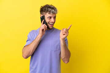 Young caucasian man using mobile phone isolated on yellow background intending to realizes the solution while lifting a finger up