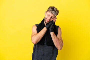 Sport caucasian man isolated on yellow background making sleep gesture in dorable expression