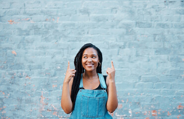 Black woman fingers pointing to advertising mockup or marketing space on blue wall outdoor youth...