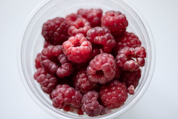 glass of raspberries seen from above on a white table