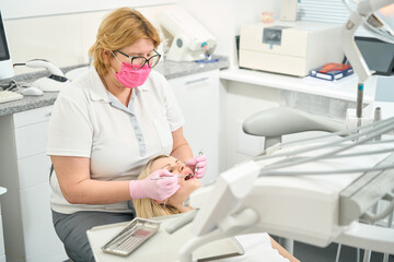 Caucasian woman doctor in glasses treats teeth