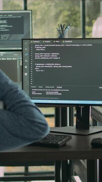 Vertical video: Asian system engineer working with html script on computer screen, using terminal window. Software developer coding system interface, writing innovating ai algorithm in office space.