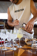 Young man preparing cocktail with shaker. Summer holiday, party concept.