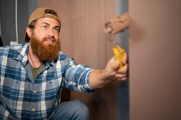 Portrait of a bearded painter painting a wall with a paint roller