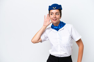 Airplane stewardess caucasian woman isolated on white background listening to something by putting hand on the ear