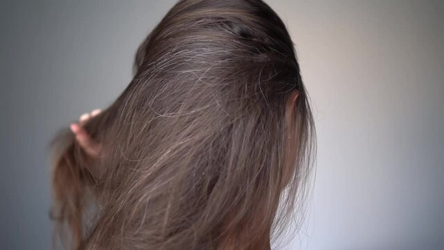 A woman combs her hair. Gray hairs on the head of a young girl. Long gray hair. The initial stage of gray hair. The problem of gray hair in women.