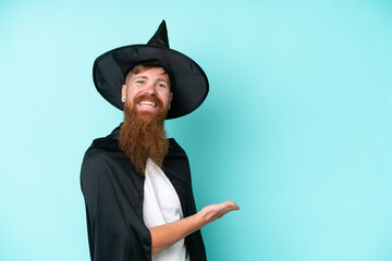 Young wizard in halloween isolated on blue background extending hands to the side for inviting to...