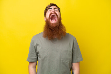 Redhead man with beard isolated on yellow background shouting to the front with mouth wide open