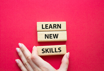 Learn new skills symbol. Concept words Learn new skills on wooden blocks. Beautiful red background....