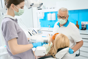 Unrecognized blonde woman is receiving dental treatment in stomatology clinic