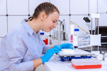 Young woman installs a microplate for DNA analysis of biological samples work with PCR robot